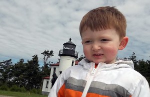 Max standing by the lighthouse, wholly unaware of why he's been told to smile.
